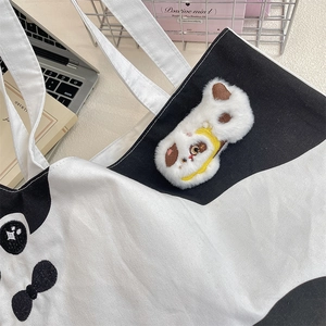 Detail of canvas tote bag featuring plush cartoon dog pin and bow embroidery