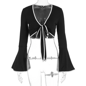 Detail of black lace-up crop top with flared sleeves and contrast white piping