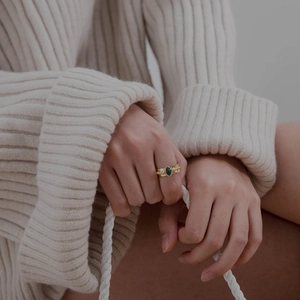Detail of 18K gold-plated hammered ring with oval green gemstone worn on model's finger