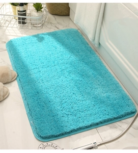 Plush turquoise bathroom mat on marble floor with cozy slippers and home decor