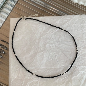Minimalist black beaded necklace with silver accents and adjustable clasp on white paper