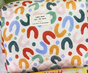 Detail of quilted cotton toiletry bag featuring colorful abstract patterns and fabric label