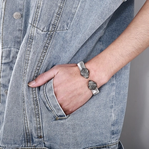 Detail of a punk snake head stainless steel bracelet worn with denim jeans for men