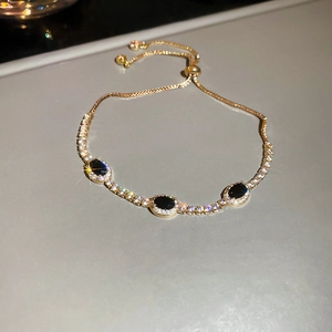 Macro shot of adjustable gold bracelet with oval black zircon and small white stones
