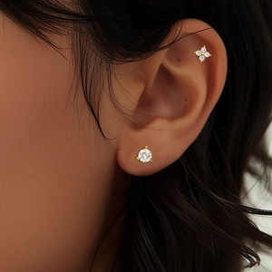 Close-up of gold S925 silver clover and round stud earrings on a female model