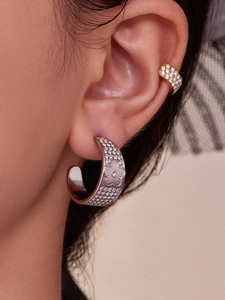 Detailed macro view of crystal-studded flower earrings and gold pave ear cuffs