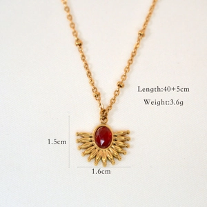 Macro shot of 14k gold plated fan-shaped pendant with red natural stone inlay