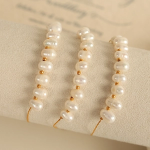 Ensemble de bracelets en perles d'eau douce et or présenté sur un rouleau en tissu beige
