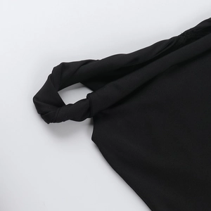 Dettaglio del design della tracolla a torsione nera su questa elegante tuta alla moda