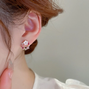 Dettaglio orecchino a fiore scintillante con cristalli rosa indossato su modella