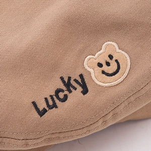 Dettaglio berretto kaki per bambini con ricamo Lucky e toppa a forma di orso