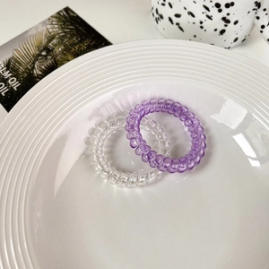 Top view of purple and transparent spiral hair ties on a ceramic plate with ins style decor