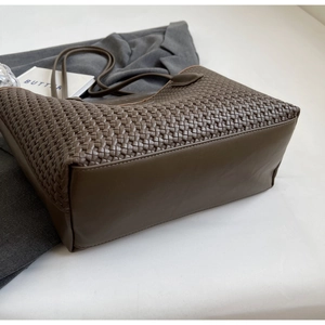 Detail of dark brown woven tote bag showing leather texture and structured base design