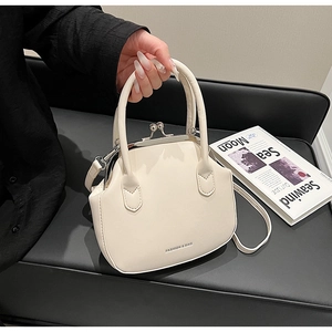 Close-up of minimalist off-white shell handbag with metallic clasp and fashion text