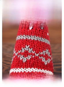Macro detail of red knit Christmas gnome decoration showing geometric weave patterns
