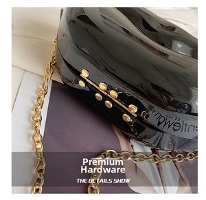 Close-up of black glossy lip-shaped purse with gold chain and premium hardware details