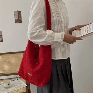 Detalle del bolso tote de felpa roja con etiqueta de cuero y forro de cuadros