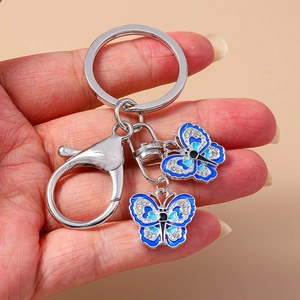 Handheld silver keychain featuring two blue enamel butterfly pendants with rhinestones