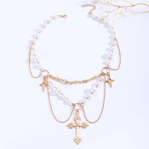 Detail of layered gold necklace with white pearls, cross pendant and star charms