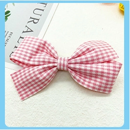 Close-up of pink and white checkered knit fabric bow hair clip for children girls