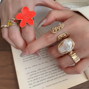Detailed shot of retro gold rings featuring orange flower and baroque pearl details