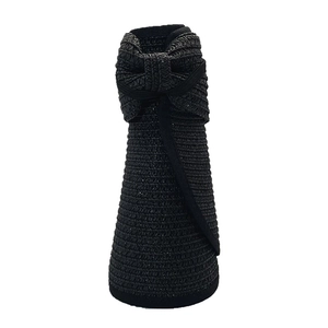 Detail of the compact foldable black straw hat with a decorative bow knot for easy travel