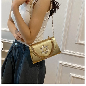 Detail of gold chain crossbody bag featuring a rhinestone sunflower buckle and metallic finish