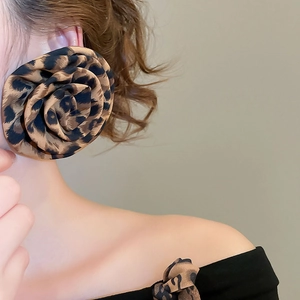 Macro detail of fabric leopard print flower earrings on model with soft lighting