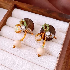 Handgefertigte Boho-Ohrringe mit Kokosschale und Glasperlen in einer hölzernen Schmuckschatulle