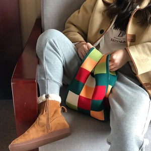 Knitted tote bag with colorful checkerboard pattern held by a model in casual winter outfit