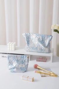 Detail of blue floral jacquard makeup bags in two sizes with metal flower zipper pull