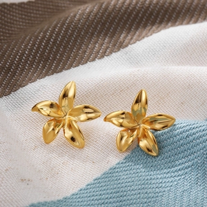Macro detail of 18k gold flower earrings with polished petals on textured fabric