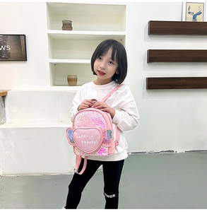 Pink sequin kids mini backpack featuring heart-shaped pocket and wings on model