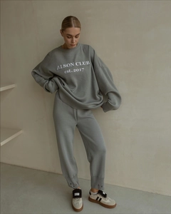 Detail of grey knitted sweater set with ALSON CLUB embroidered logo on chest