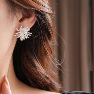 Close-up of sparkling silver firework flower stud earrings worn by a model