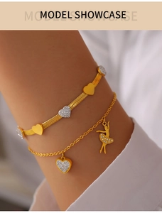 Detail of layered gold bracelets with heart pendants and sparkling ballerina charm