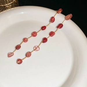 Detailed close-up of strawberry crystal tassel earrings with long gold chain and red gems