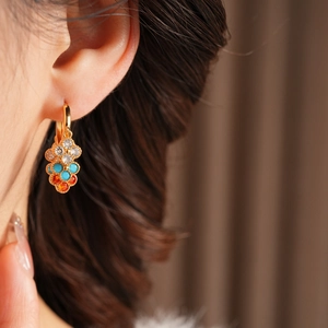 Close-up of gold flower tassel earrings with multicolored zircon stones on model