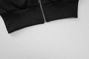 Detail view of the ribbed hem and silver metal zipper on this black knitted jacket