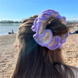 Detailed shot of a purple and beige crochet ruffle scrunchie on long brown hair