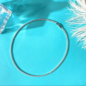 Sparkling tennis necklace with clear cubic zirconia on a vivid blue textured background