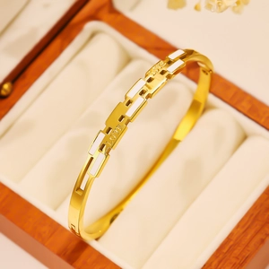 Macro shot of gold stainless steel bangle with LOVE engraving in a wooden jewelry box