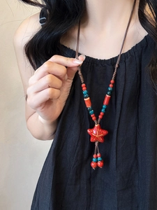Detail of handmade star pendant necklace on model with braided rope and colorful beads