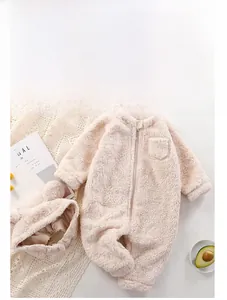 Detailed view of plush beige baby romper with hood and zipper on a flat lay background