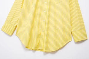 Detail of yellow striped shirt showing white resin buttons and neat stitching on fabric