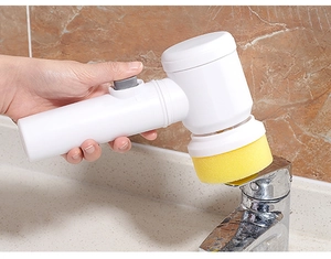 Close-up of electric cleaning brush with sponge head scrubbing a faucet in the kitchen