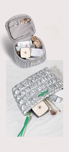 Detailed view of silver quilted makeup bag featuring green woven drawstring closure
