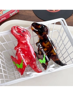 Detail of two dinosaur acetate hair claws in red and tortoise shell in a white basket