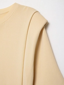 Close-up of ribbed round neck and structured pleat shoulder on a beige knit top