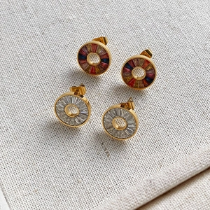 Detail of gold circular earrings with colorful and clear baguette crystals on linen